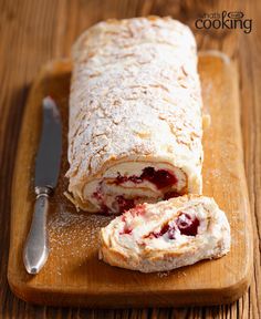 a pastry roll is cut in half on a cutting board next to a knife and fork