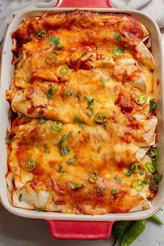 a red casserole dish filled with chicken, cheese and green pepper toppings