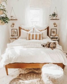 a cat laying on top of a bed in a room with white sheets and pillows