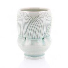 a white and blue vase with lines on it's sides, sitting on a white surface