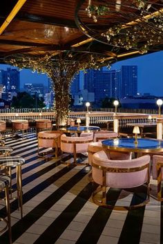 an outdoor dining area with tables, chairs and plants on the roof terrace at night