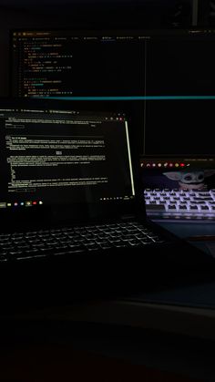 a laptop computer sitting on top of a desk next to a mouse and keyboard in the dark