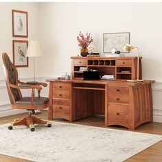 a wooden desk with a chair and lamp on top of it next to a rug