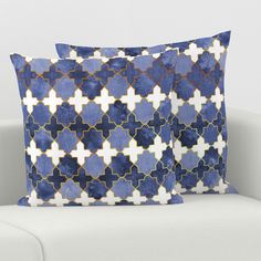 two blue and white pillows sitting on top of a couch