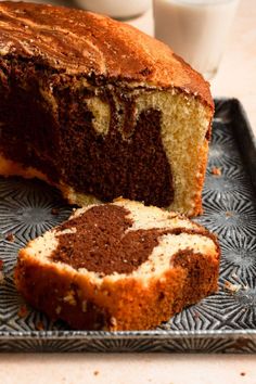 a loaf of chocolate marbled cake on a plate next to a slice cut from it