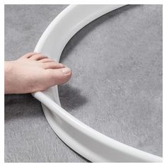 a person's hand is holding onto the edge of a white circular object on a gray surface