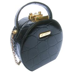 St John embossed vinyl diminutive size handbag - shoulder bag c 1990 The stylish compact size rounded purse is covered with embossed patent black vinyl that emulates reptile skin Designed with a sleek gilt metal latch clasp mechanism. Adorned with a gilt metal plaque inscribed St John on the front exterior. Paired with a detachable gilt metal shoulder strap chain Transitions from a small size handbag; transitions into a stylish compact size shoulder bag carried with the gilt metal chain strap Th Classic Round Case Bags For Daily Use, Classic Round Case Bag For Daily Use, Formal Satchel Evening Bag, Compact Formal Bag With Gold-tone Hardware, Compact Formal Bags With Gold-tone Hardware, Formal Compact Bag With Gold-tone Hardware, Compact Leather Bag, Formal Crossbody Evening Bag, Compact Portable Leather Bag