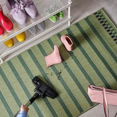 a person using a blow dryer on a rug next to shoes and other items