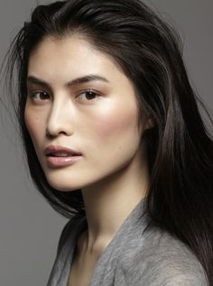 a woman with long dark hair wearing a gray top and grey cardigan sweater, posing for the camera