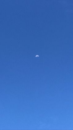 an airplane flying in the blue sky with a half moon on it's side