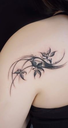 a woman's back shoulder tattoo with flowers and leaves on the upper half of her arm