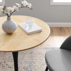 a vase with white flowers and a book on a small table in a living room