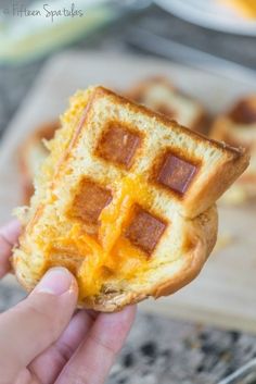 a person holding up a waffle with cheese on it