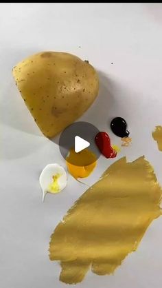 a potato sitting on top of a piece of paper next to some paint and an egg