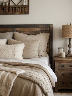 a bed with pillows and blankets on top of it next to a night stand in a bedroom