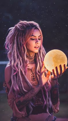 a woman with dreadlocks holding an illuminated orb