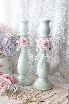 two light blue vases with pink roses on them sitting next to lace doily