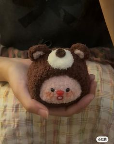 a person holding a small stuffed animal in their hands and wearing a knitted hat