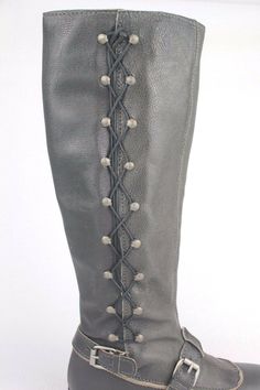 Grey boots make an excellent accompaniment to almost any outfit. Metal studs run vertically up the side with leather laces. Together the leather strap around the arch gives and tan trim around the base of your toes gives these boots an equestrian feel with a unique tailored twist. Approx: 1/4" heel Shiny studs add edgy style to these tall leather boots from J. Litvack. Featuring a round toe, dual adjustable ankle straps with side buckle closure, and leather weaving throughout the side studs. Tan Trim, Tall Leather Boots, Grey Boots, The Arch, Edgy Style, Leather Weaving, Leather Buckle, Moto Boots, Ankle Straps