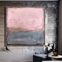 an abstract painting hangs on the wall above a blue chair in a modern living room