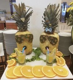 there are pineapples and orange slices on the table with juice in glasses next to them