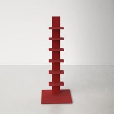 a tall red book shelf sitting on top of a white floor