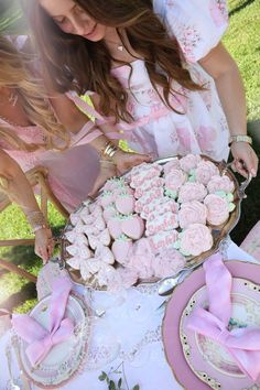 a woman standing over a table filled with cupcakes