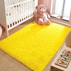 a teddy bear sitting on a yellow rug in a child's room next to a crib