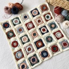 a crocheted granny's square with balls of yarn next to it