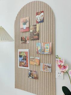 a wall mounted bulletin board with pictures on it and flowers in the corner next to it