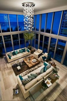 a living room filled with lots of furniture and large windows overlooking the city at night