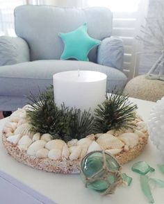 a candle is sitting on a table with shells and sea glass in front of it