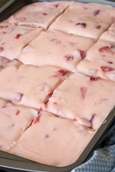 a pan filled with white chocolate covered in pink icing and cranberry toppings