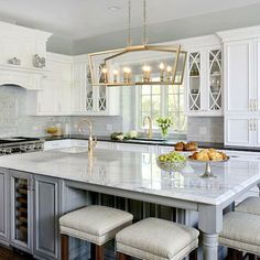 a large kitchen with white cabinets and marble counter tops