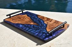 a wooden tray sitting on top of a table next to a body of blue water