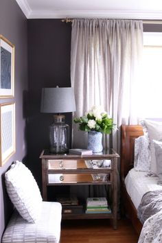 a bed room with a neatly made bed and a night stand next to a window