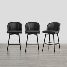 three black bar stools in front of a white wall