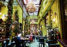 the inside of a restaurant with green walls and plants hanging from the ceiling, along with tables and chairs