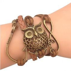 an owl bracelet is on the arm of a woman wearing a brown leather wrap around it