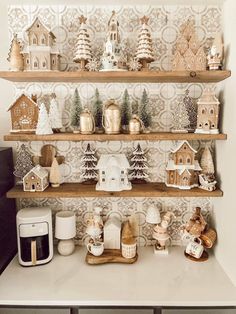 christmas decorations are displayed on shelves in the corner of a room with white and gold wallpaper