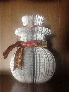 an origami snowman made out of folded book pages on a table top