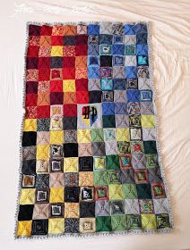 a quilt made with squares and pictures is laying on top of a white bed sheet