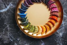 an assortment of colorful fruits arranged in a circle on a plate with marble counter top