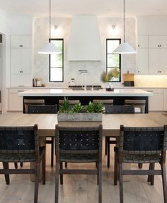 a large kitchen with an island and dining table in the center, surrounded by chairs