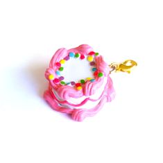 a pink ring with sprinkles on it and a gold keychain