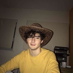 a young man wearing a cowboy hat in his living room