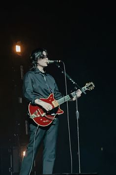 a man standing on top of a stage holding a guitar