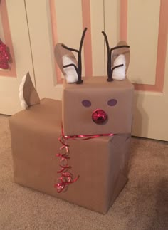 a cardboard box with reindeer antlers on its head and ribbon around the eyes, tied to it