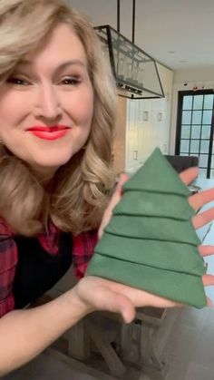 a woman holding up a folded christmas tree