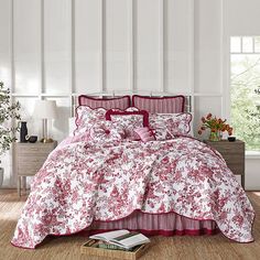 a bed with red and white comforters in a room